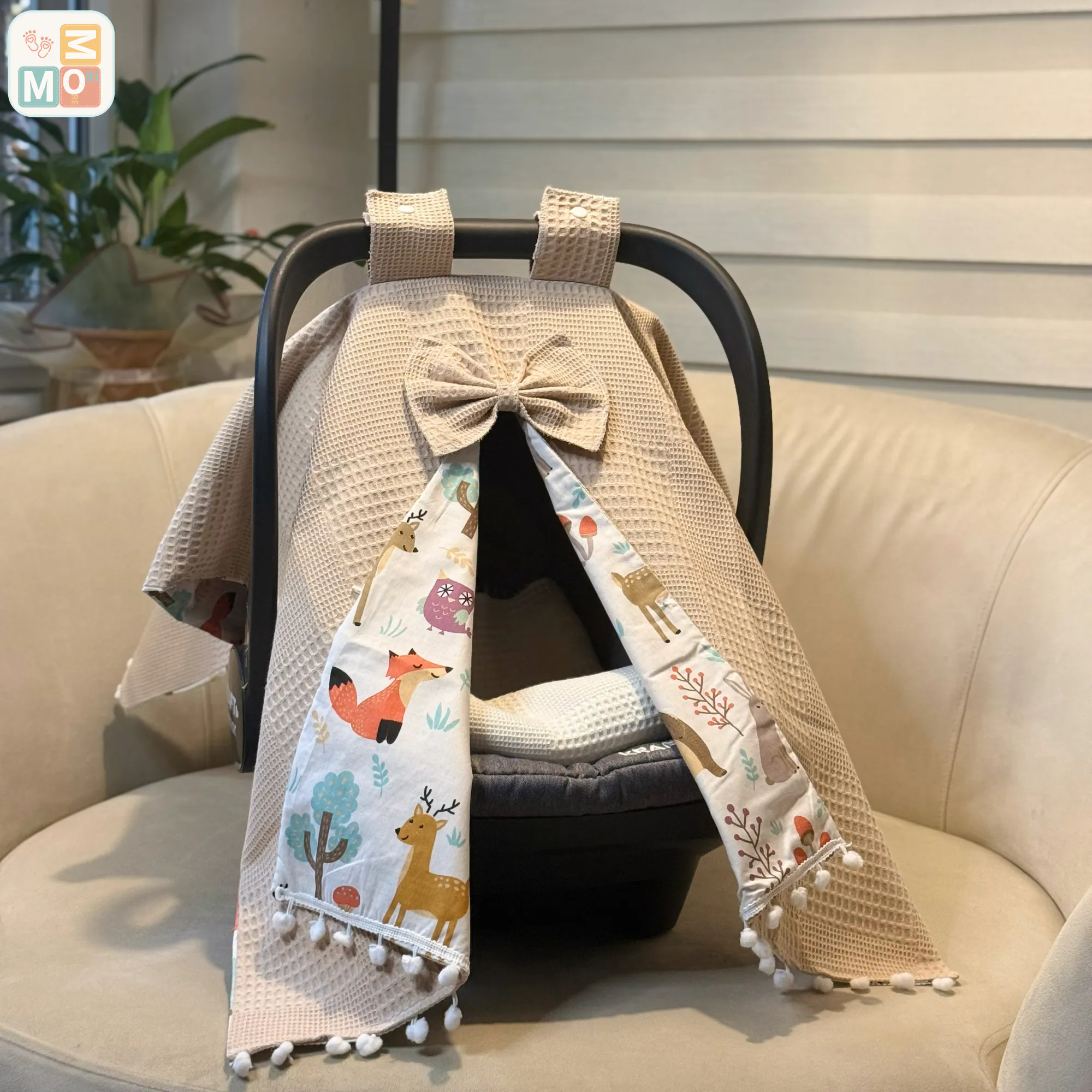 Waffle cotton baby car seat canopy with printed poplin lining, bow detail, and pom pom trim on an infant car seat.