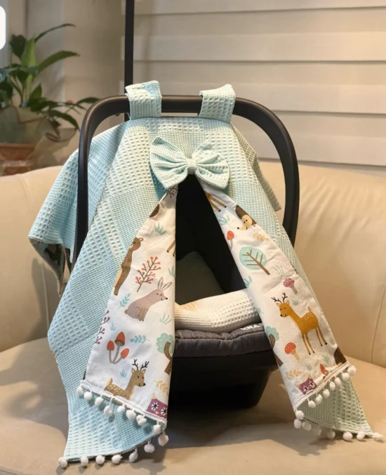 Waffle cotton baby car seat canopy with printed poplin lining, bow detail, and pom pom trim on an infant car seat. Aqua Blue